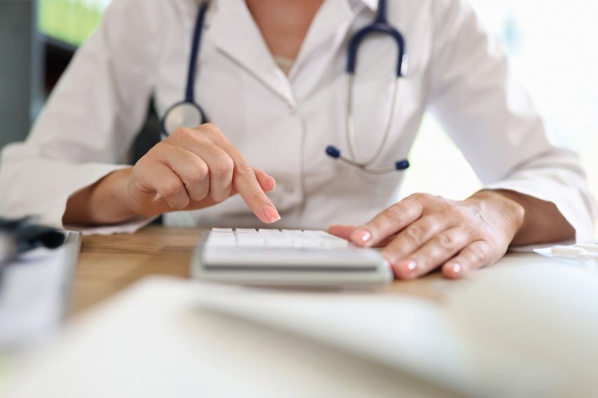 Foto: Ärztin arbeitet auf Taschenrechner im Büro